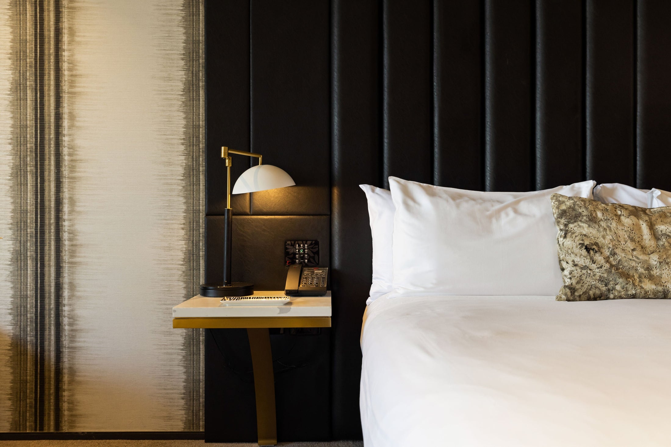 Bedroom with a bed and nightstand against a dark paneled wall at Emporium Hotel.