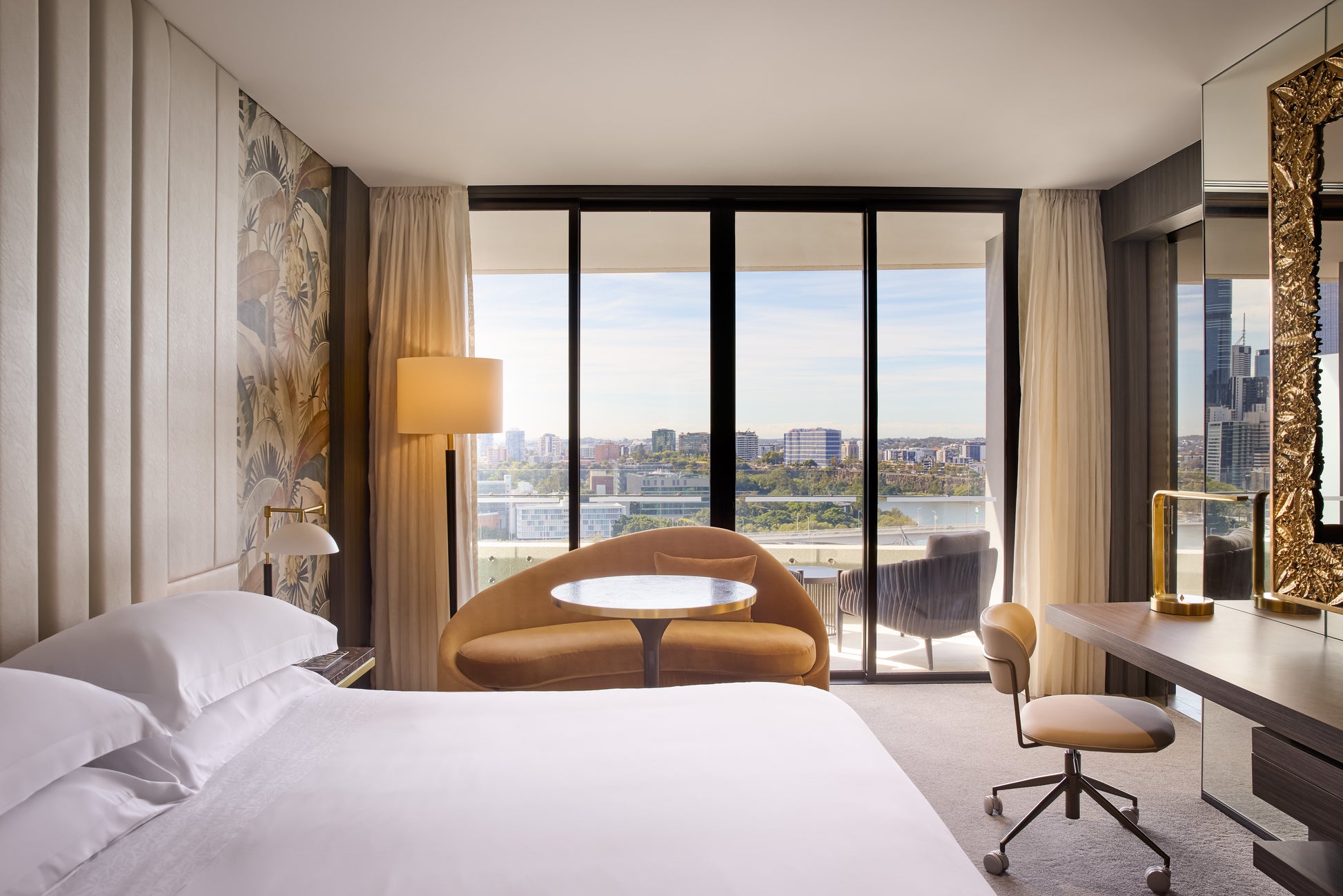Modern bedroom with a city view, bed, desk, and chair.